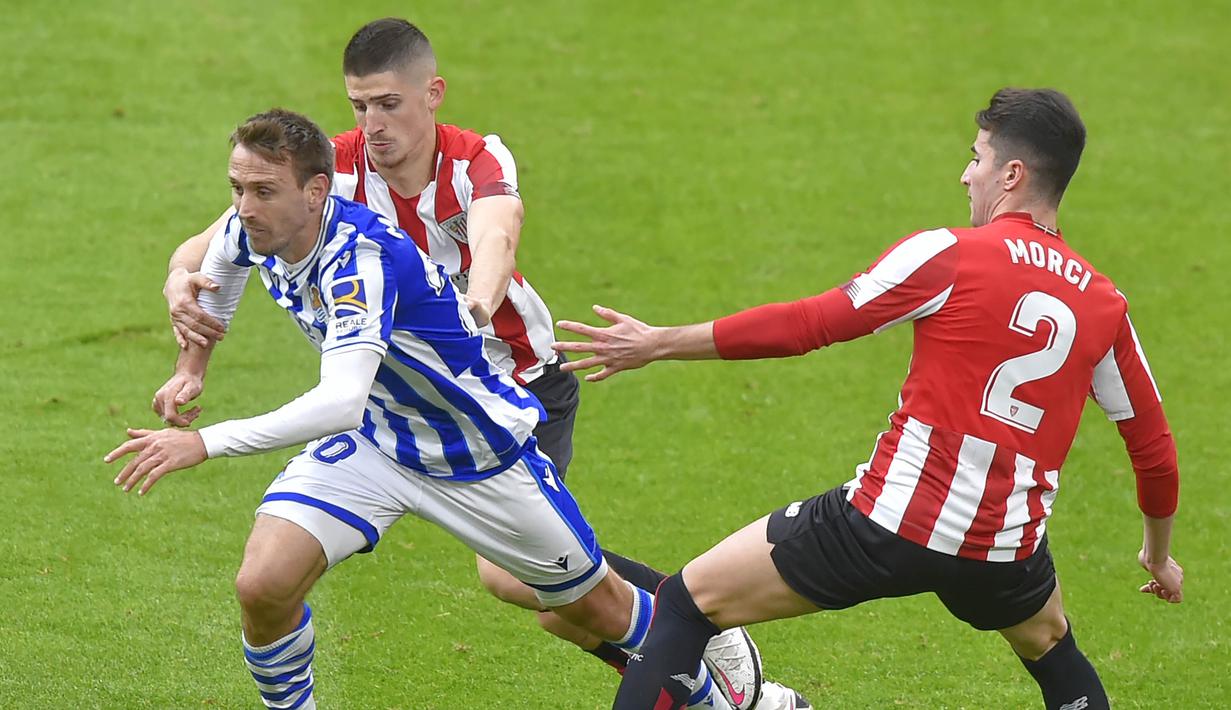Pemain Real Sociedad, Nacho Monreal, berusaha melewati pemain Athletic Bilbao pada laga liga Spanyol di Stadion San Mames, Kamis (31/12/2020). Real Sociedad menang dengan skor 1-0. (AFP/Ander Gillenea)