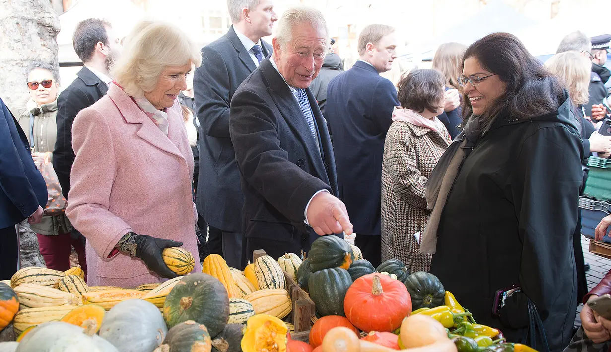 Pangeran Charles bersama istrinya, Duchess of Cornwall Camilla berbincang dengan pedagang ketika mengunjungi Swiss Cottage Farmers Market di London utara, Rabu (6/11/2019). Kunjungan Charles dan Camila untuk memperingati ulang tahun ke-20 pasar tersebut. (Eddie Mulholland / POOL / AFP)
