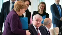 Angela Merkel mengulurkan tangan untuk menyambut Horst Seehofer pada sebuah pertemuan tentang migrasi di Berlin. (AFP / John MACDOUGALL)