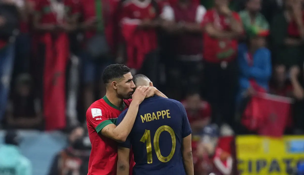 Bek Maroko Achraf Hakimi merangkul penyerang Prancis Kylian Mbappe setelah babak semifinal Piala Dunia 2022 di Al Bayt Stadium, Kamis (15/12/2022) dini hari WIB. Momen menarik tersaji sesaat setelah laga berakhir, Mbappe pun tertangkap kamera langsung menghibur Hakimi. (AP Photo/Natacha Pisarenko)