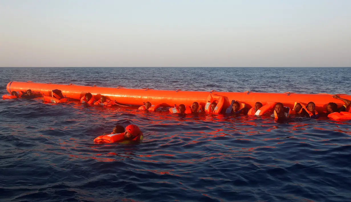Sejumlah imigran memegang pelampung saat menunggu diselamatkan oleh petugas di lepas panti Libya, Laut Mediterania, Senin (29/8). Para penjaga pantai Italia berhasil menyelamatkan sekitar 6.500 imigran dari Eritrea dan Somalia. (REUTERS/Giorgos Moutafis)