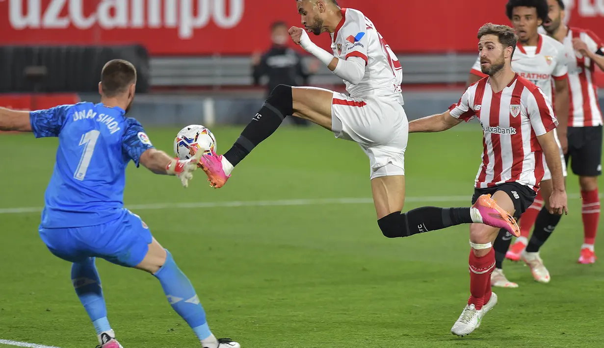 Penyerang Sevilla, Youssef En-Nesyri (tengah) berusaha mengontrol bola dari kawalan kiper Athletic Bilbao, Unai Simon pada pertandingan lanjutan La Liga Spanyol di stadion Ramon Sanchez Pizjuan di Seville, Selasa (4/5/2021). Atletico Bilbao menang atas Sevilla 1-0. (AFP/Cristina Quicler)