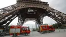 Kendaraan petugas penyelamat terparkir di bawah Menara Eiffel, Paris, Senin (20/5/2019). Menara Eiffel ditutup bagi pengunjung setelah seseorang pria berusaha memanjat bangunan ikonik tersebut tanpa izin. (AP/Michel Euler)