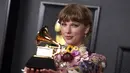 Taylor Swift berpose dengan penghargaan album tahun ini untuk "Folklore" di Grammy Awards tahunan ke-63 di Los Angeles Convention Center (14/3/2021). Album ini ditulis dan dirilis Taylor Swift sebagai sebuah proyek kejutan dan dadakan selama pandemi berlangsung. (AP Photo/Jordan Strauss)