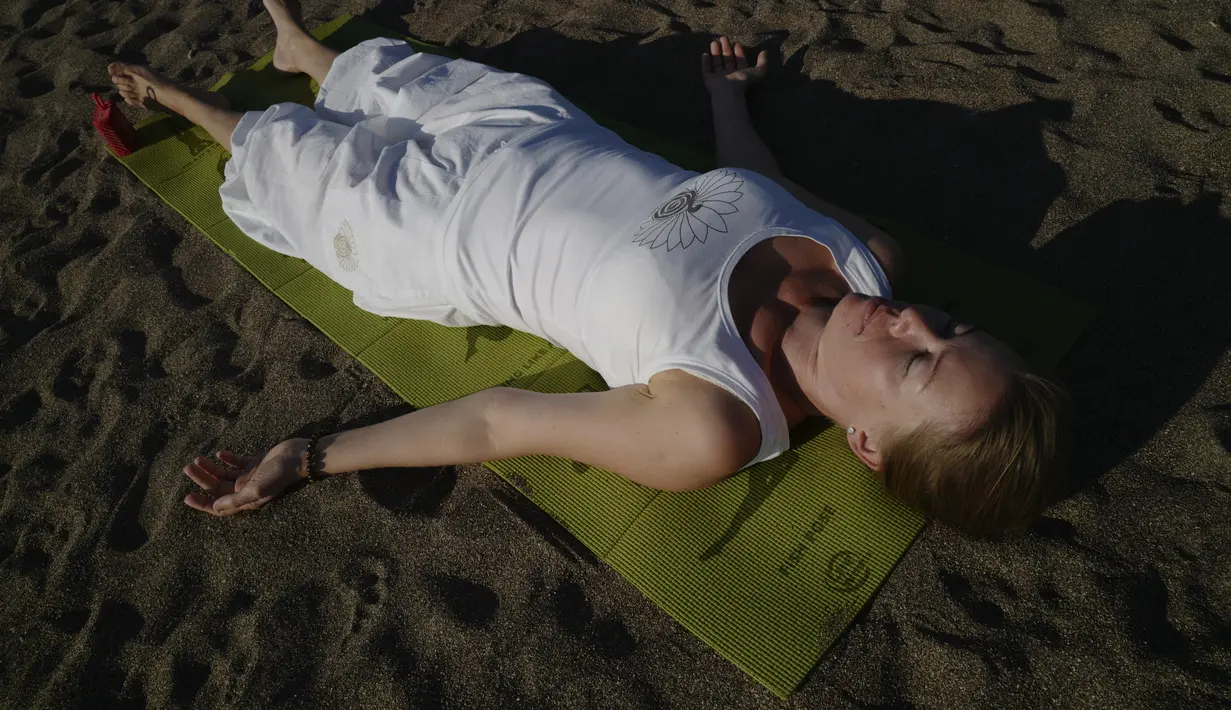 Seorang wanita berlatih yoga di pantai di Adrasan, barat Antalya, Turki (24/9/2021). Orang-orang menikmati cuaca hangat di wilayah Mediterania saat salju pertama menyelimuti pegunungan tinggi di timur laut Turki. (AP Photo/Burhan Ozbilici)