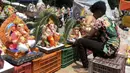 Seorang pekerja memajang patung Dewa Ganesha untuk dijual di kios pinggir jalan di Hyderabad, India, Kamis (9/9/2021). Patung dewa Hindu berkepala gajah tersebut banyak dijual jelang Festival Ganesh Chaturthi. (NOAH SEELAM/AFP)