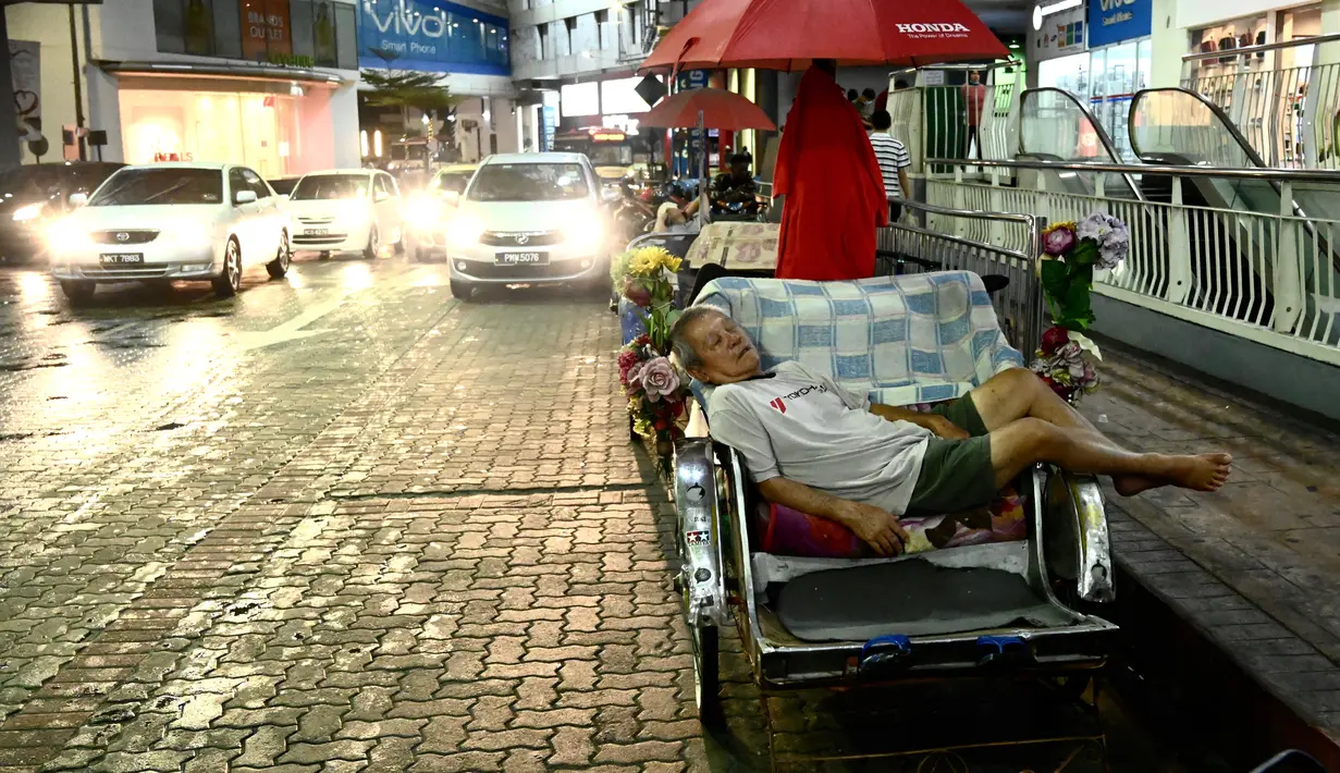 Pengemudi becak tidur siang di luar pusat perbelanjaan di Penang (1/8/2020). Malaysia tengah memperingatkan gelombang kedua virus corona COVID-19. (AFP Photo/Goh Chai Hin)