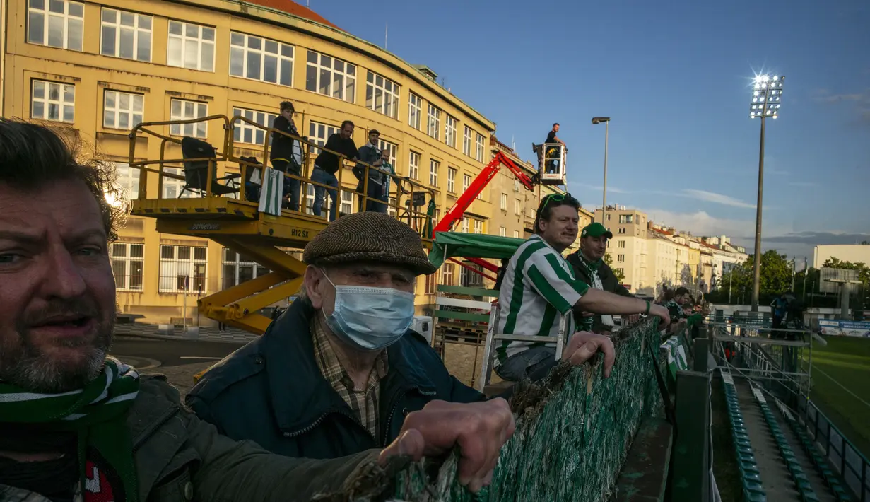 Suporter Bohemians 1905 menyaksikan pertandingan melawan Sparta Praha pada laga Liga Fortuna di Praha, Rep. Ceko (6/6/2020). Laga tertutup karena pembatasan virus corona tersebut membuat fans menonton dari balik tembok. (AFP/Michal Cizek)