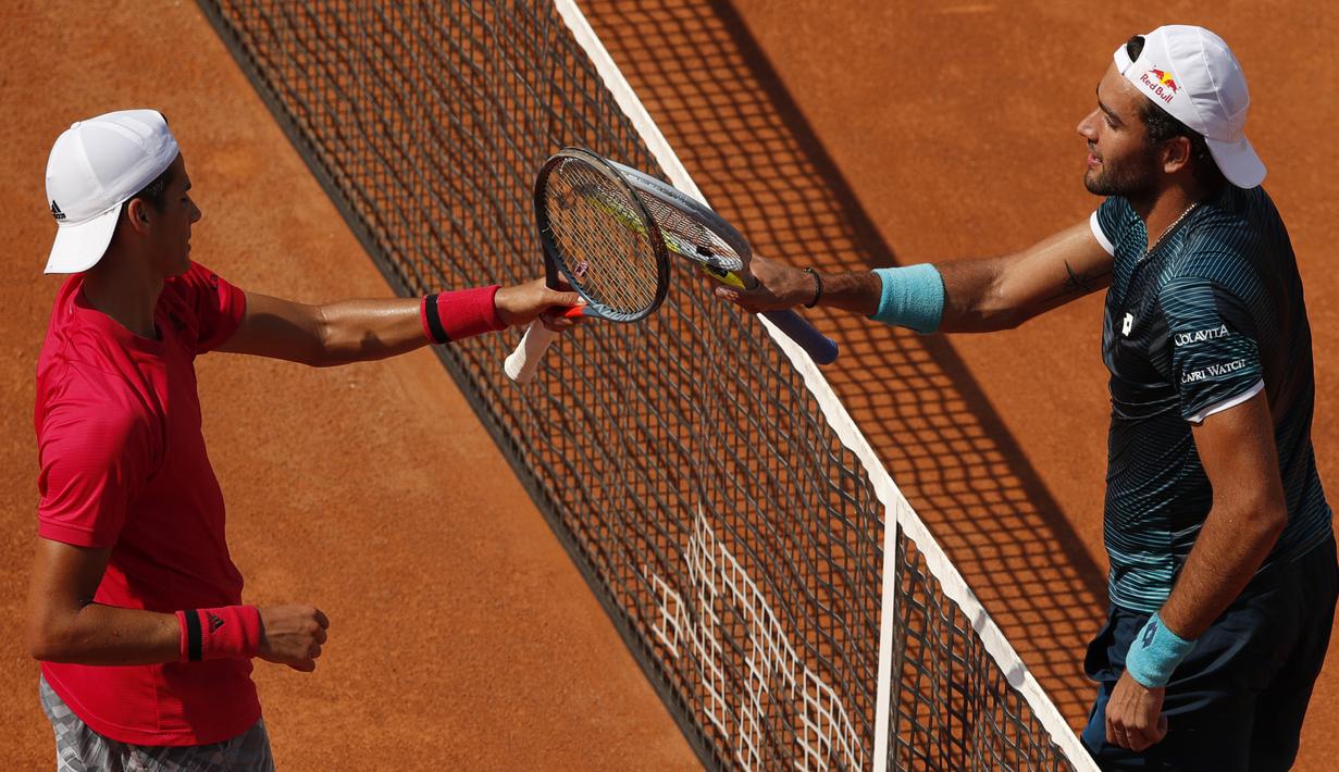 Petenis Argentina Federico Coria dan petenis Italia Matteo Berrettini bersalaman dengan cara mengetuk raket di akhir pertandingan Italia Open di Foro Italico, Rabu (16/9/2020). (AFP/Clive Brunskill/pool)