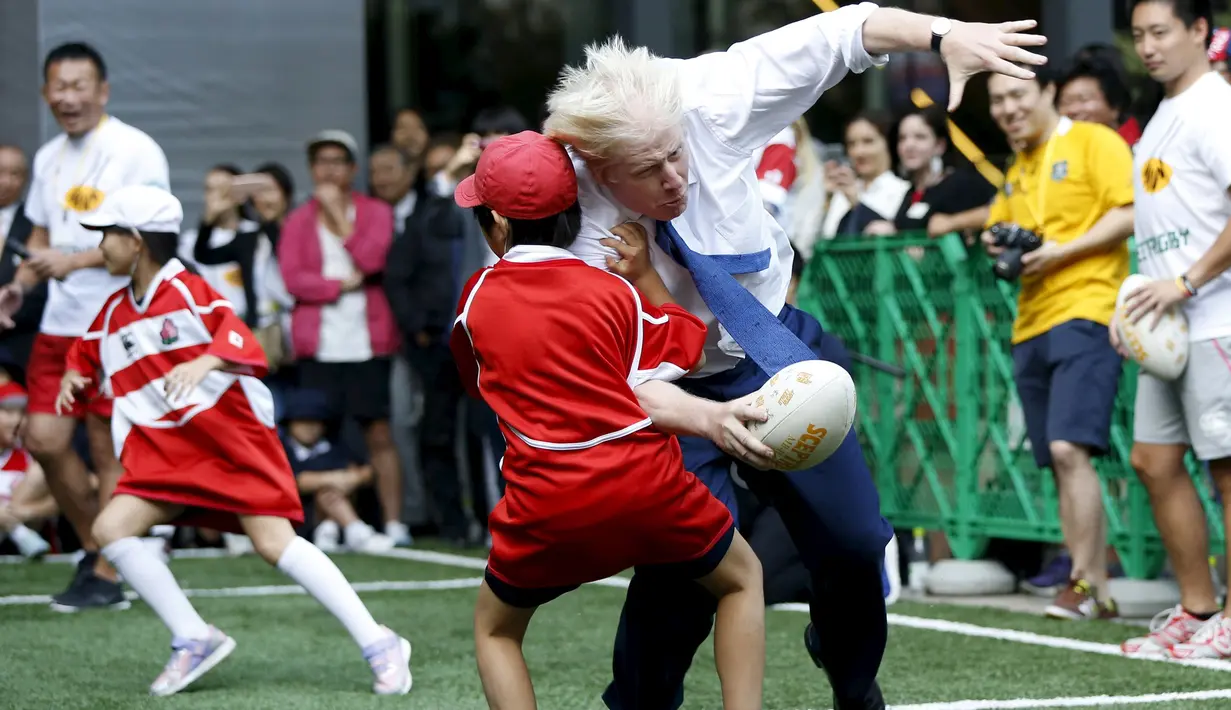 Walikota London Boris Johnson (kanan) bertabrakan dengan seorang anak selama bermain Rugby, Tokyo, Jepang, Kamis (15/10/2015).  Boris bermain Rugby untuk menyambut Jepang sebagai tuan rumah Piala Dunia Rugby 2019. (REUTERS/Issei Kato) 