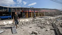 Seorang pria berjalan di tengah puing-puing bangunan yang rusak akibat gempa berkekuatan magnitudo 7,7 di Borong, Manggarai Timur, Nusa Tenggara Timur, Minggu, 16 Agustus 2026.. (AFP/ Juni Kriswanto)