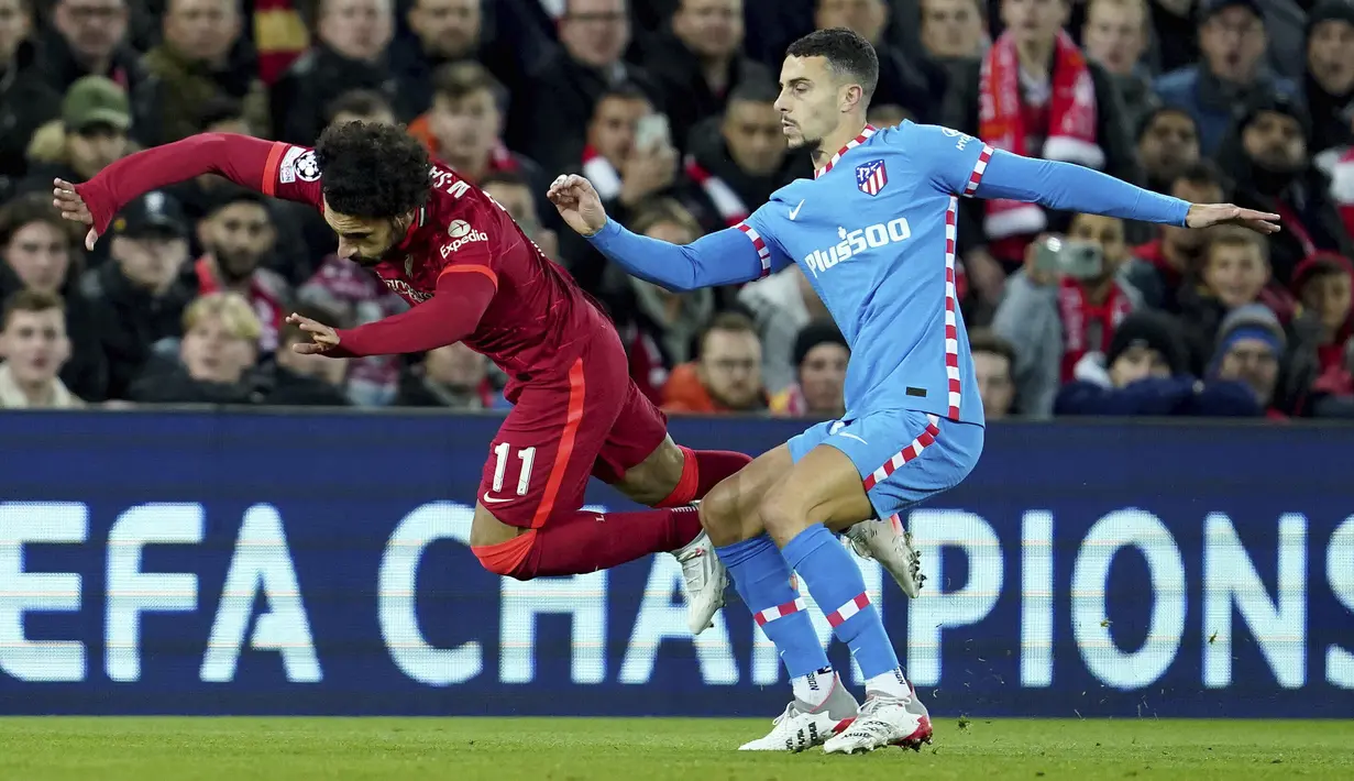 Penyerang Liverpool Mohamed Salah (kiri) dilanggar oleh bek Atletico Madrid Mario Hermoso pada match day ke-4 Liga Champions di Anfield, Kamis (4/11/2021) dinihari WIB. Liverpool menyegel satu tempat di babak 16 besar Liga Champions usai menundukkan Atletico Madrid 2-0. (AP Photo/Jon Super)