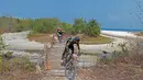 Para pebalap Mountain Bike Cross Country Marathon melintasi jembtan kayu pada Festival Pesona Tanjung Lesung 2017 di Tanjung Lesung, Banten (23/9/2017). MTB XCM tersebut menempuh jarak 48 km. (Bola.com/Nicklas Hanoatubun)