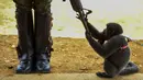 Tingkah seekor monyet saat bermain dengan senjata polisi wanita di Agua Bonita, Kolombia (25/10). Monyet ini asyik bermain dengan senjata laras panjang milik polwan tersebut. (AFP Photo/Raul Arboleda)