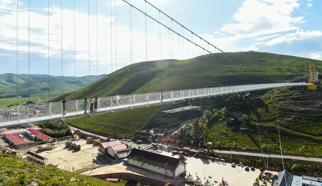 Wisatawan berjalan di atas jembatan gantung berlantai kaca di kawasan wisata nasional Hongshiya di Wilayah Zhuozi, Ulanqab, Daerah Otonom Mongolia Dalam, China utara, pada 15 Agustus 2020. (Xinhua/Peng Yuan)