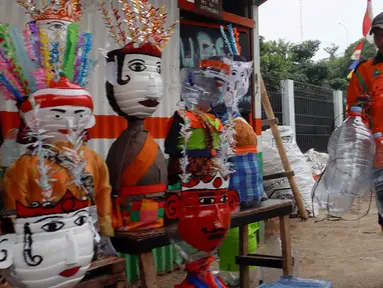 Petugas Unit Penanganan Sampah (UPS) Badan Air (BA) Dinas Lingkungan Hidup DKI Jakarta Kecamatan Jatinegara membuat ondel-ondel mini dari galon air minum bekas di Jakarta, Selasa (25/6/2024). (Liputan6.com/Herman Zakharia)