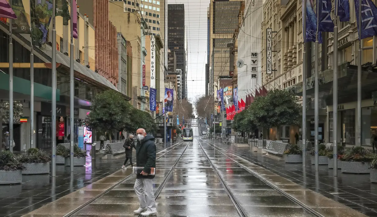 Seorang pria bermasker berjalan melalui Bourke Street Mall yang tenang di Melbourne, Jumat (16/7/2021). Kota terbesar kedua di Australia itu kembali memberlakukan lockdown, dan kali ini selama lima hari mulai Kamis (16/7) malam karena meningkatnya klaster COVID-19. (ASANKA BRENDON RATNAYAKE/AFP)