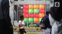 Pejalan kaki melintas dekat layar pergerakan Indeks Harga Saham Gabungan (IHSG) di kawasan Jakarta, Senin (13/1/2020). IHSG sore ini ditutup di zona hijau pada level 6.296 naik 21,62 poin atau 0,34 persen. (Liputan6.com/Angga Yuniar)