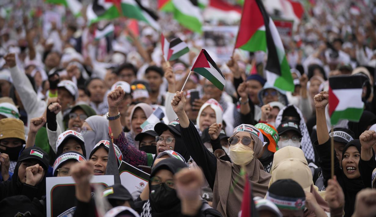 Massa meneriakkan slogan-slogan dan mengibarkan bendera Palestina saat aksi bela Palestina, di Monumen Nasional atau Monas, Jakarta Pusat, Minggu (5/11/2023). (AP Photo/Dita Alangkara)