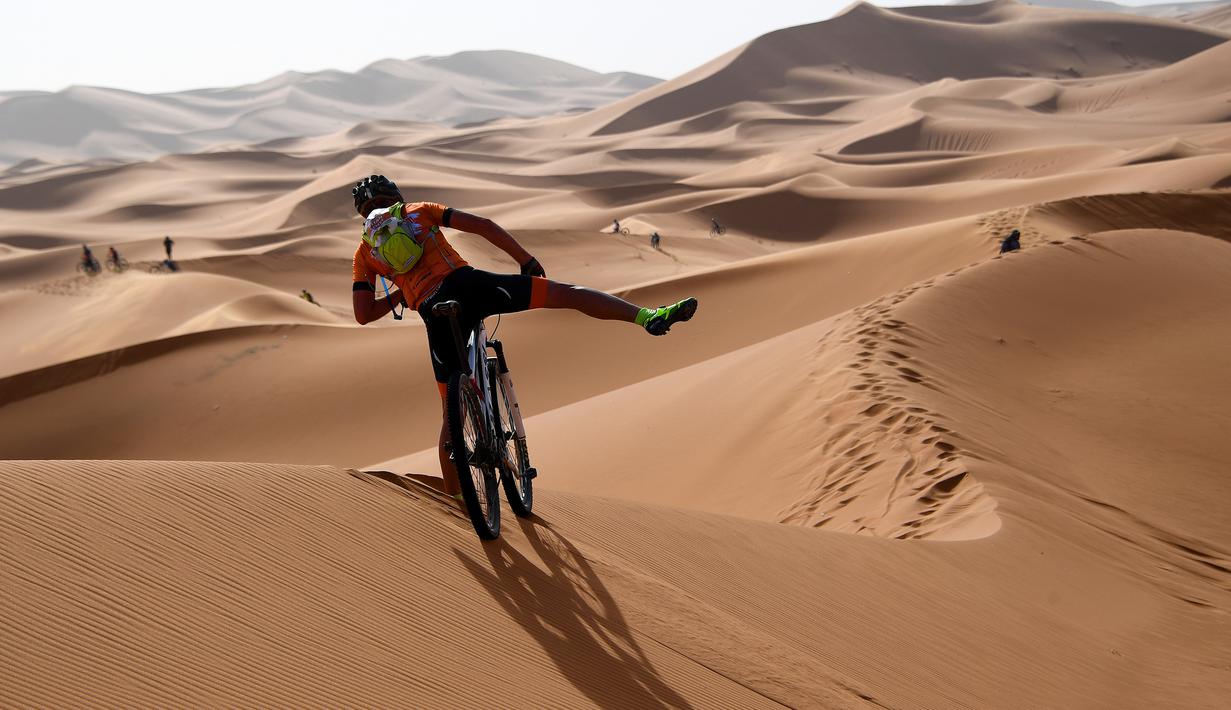 Pebalap mengendarai sepeda melintasi sepanjang bukit pasir pada etape 1 edisi ke 14 balap sepeda gunung Titan Gurun 2019 di sekitar Kota Merzouga, Maroko, Minggu (28/4/2019). Trek Titan Gurun 2019 sepanjang 640 km menghubungkan antara Merzouga dan Maadid. (Franck Fife / AFP)