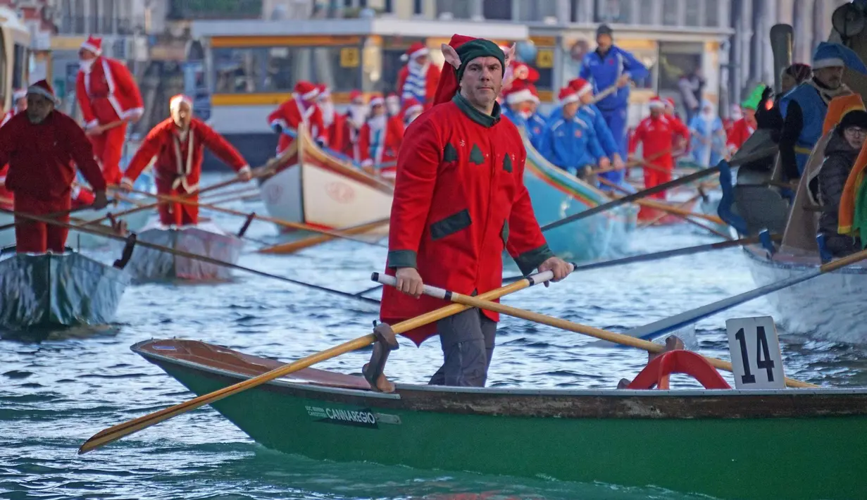 Ratusan orang mengenakan kostum Santa Claus mendayung perahu di Canal Grande di Venesia, Italia, (17/12). Hampir seratus perahu dayung tradisional, dengan berbagai jenis dan ukuran berparade di sepanjang Grand Canal. (Andrea Merola / ANSA via AP)