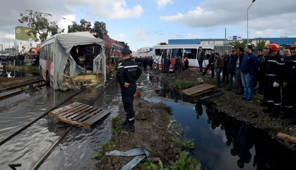 Sejumlah orang berkumpul di lokasi kecelakaan antara kereta dengan sebuah bus di rel dekat wilayah Sidi Fathallah, sekitar 10 km selatan Ibu Kota Tunisia, Rabu (28/12). Penyelidikan tengah dilakukan untuk mencari tahu apa yang terjadi. (Fethi Belaid/AFP)