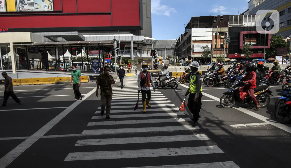 Warga menyeberang jalan menggunakan pelican crossing di kawasan Glodok, Jakarta, Sabtu (22/1/2022). PT Transportasi mulai mengoperasikan Halte Glodok baru dengan rute Blok M - Kota (Koridor 1). (Liputan6.com/Johan Tallo)