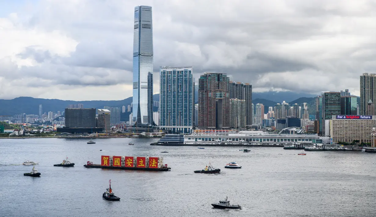 Kapal tongkang dengan spanduk bertuliskan “Rayakan Hukum Keamanan Nasional” berlayar di Victoria Harbour pada peringatan 23 tahun penyerahan Hong Kong dari Inggris ke China di Hong Kong, Rabu (1/7/2020). Hong Kong menandai 23 tahun penyerahan dari Inggris ke Cina pada 1 Juli. (Anthony WALLACE/AFP)