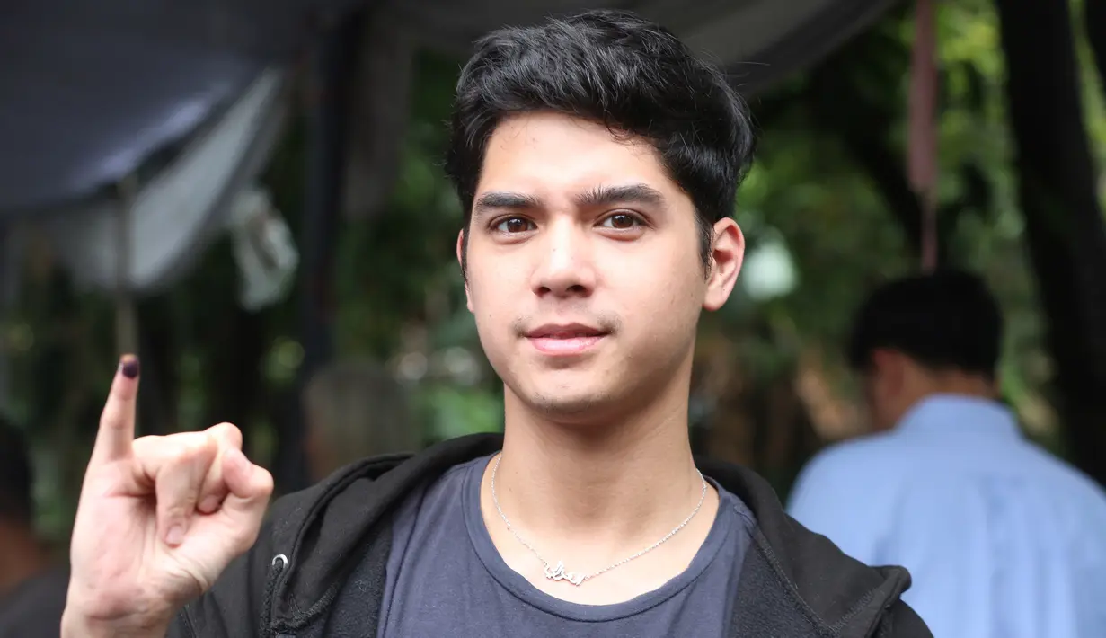 Al Ghazali yang memakai kaus serta hoodie sebagai outter, tampak ganteng. Ia pun menunjukkan jarinya yang telah tercelup tinta [Kapanlagi/Budi Susanto]