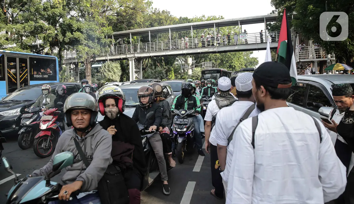 Peserta aksi reuni 212 berjalan saat kendaraan terjebak kemacetan di kawasan Jalan Thamrin dan Merdeka Barat, Jakarta, Senin (2/12/2019). Sejumlah ruas jalan di Jakarta mengalami kemacetan parah akibat aksi reuni 212 di kawasan Monas. (Liputan6.com/Faizal Fanani)