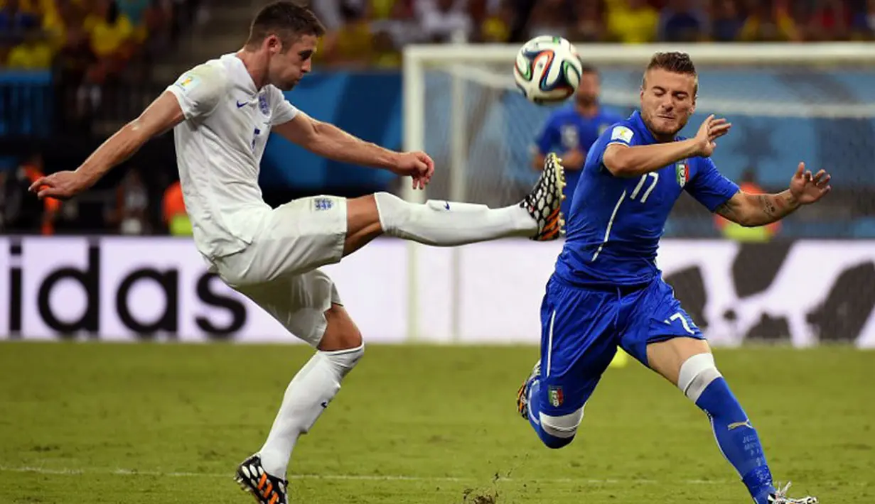 Pemain belakang Timnas Inggris, Gary Cahill (kiri), berusaha menghalau bola yang mengarah ke Ciro Immobile (Italia) saat berlaga di babak penyisihan Piala Dunia 2014 Grup D di Amazonia Arena, Manaus, Brasil, (15/6/2014). (AFP PHOTO/Fabrice Coffrini)