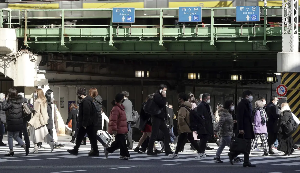 Orang-orang yang mengenakan masker pelindung untuk membantu mengekang penyebaran Virus Corona berjalan di sepanjang penyeberangan pejalan kaki di Tokyo (19/1/2021). Ibukota Jepang itu mengonfirmasi lebih dari 1.200 kasus Virus Corona baru pada 19 Januari 2021. (AP Photo/Eugene Hoshiko)