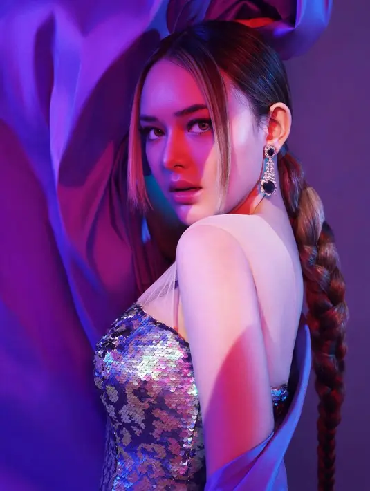 Kali ini, Amanda Manopo menghadirkan gaya yang futuristik. Dengan strapless dress bernuansa ungu yang berkilauan, Amanda Manopo memainkan kain berwarna ungu yang serasi, menambah kesan megah pada fotonya kali ini. Rambutnya disambung menjadi panjang dan dikepang satu. [Foto: Instagram/harionohalim]