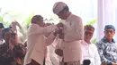 Ketua Paguyuban Pasundan Didi Turmudzi menyematkan pin warna emas berbentuk miniatur Kujang ke baju Presiden Joko Widodo (Jokowi) dalam prosesi penganugerahan gelar Pinisepuh di kota Bandung,  Jawa Barat, Minggu (11/11). (Liputan6.com/Angga Yuniar)