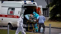 Petugas medis mengantar seorang perempuan menuju rumah sakit untuk pasien COVID-19 di pemukiman Kommunarka di luar Moskow, Rabu (30/6/2021). Rusia pada hari Rabu kembali melaporkan rekor kematian harian akibat virus Corona, dengan mencatat 669 kematian dalam 24 jam terakhir. (Dimitar DILKOFF/AFP)