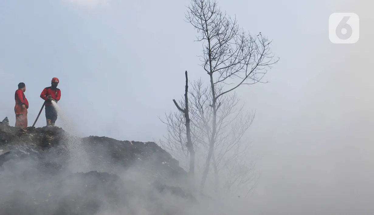 Petugas Damkar Kota Depok melakukan pendinginan tumpukan sampah yang terbakar di TPS Limo, Cinere, Depok, Jawa Barat, Senin (23/10/2023). (Liputan6.com/Herman Zakharia)
