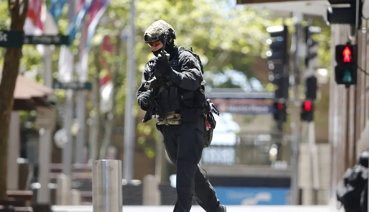 Seorang polisi berlari mengepung situasi kafe Lindt di Sydney, Australia (15/12/2014). Puluhan sandera terperangkap di dalam kafe Lindt di Sydney, Australia. (REUTERS/Jason Reed)