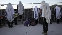 Orang-orang Yahudi Ultra Ortodoks yang ditutupi selendang berdoa saat perayaan liburan Lag BaOmer di situs makam tradisional Rabbi Shimon Bar Yochai di Gunung Meron, Israel, Kamis (19/5/2022). Orang Israel menyalakan api unggun selama perayaan Lag BaOmer untuk memperingati berakhirnya wabah yang dikatakan telah memusnahkan orang Yahudi di zaman Romawi. (AP Photo/Ariel Schalit)