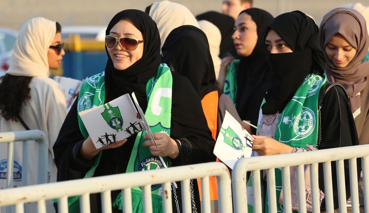 Suporter wanita Arab Saudi membawa bendera tim kesayangannya Al-Ahli saat memasuki stadion pada Saudi Pro League di King Abdullah Sports City, Jeddah, (12/1/2018). Arab Saudi untuk pertama kalinya mengizinkan wanita menonton di stadion. (AFP/STRINGER)