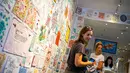 Orang-orang melihat proyek "Tiny Pricks" di toko Lingua Franca, New York City pada 25 Juli 2019. Seniman Amerika, Diana Weymar menyulam komentar-komentar Presiden Donald Trump ke dalam serbet dapur, celemek bayi, hingga pakaian dalam. (EDUARDO MUNOZ ALVAREZ / AFP)