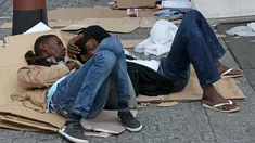 Dua orang imigran berbaring menggunakan kardus bekas sebagai alas di sebuah kamp darurat di jalanan Kota Paris, Prancis, Selasa (6/9). Para imigran berkulit hitam tersebut hidup terlantar di pinggir jalan kota tersebut. (REUTERS/Benoit Tessier)
