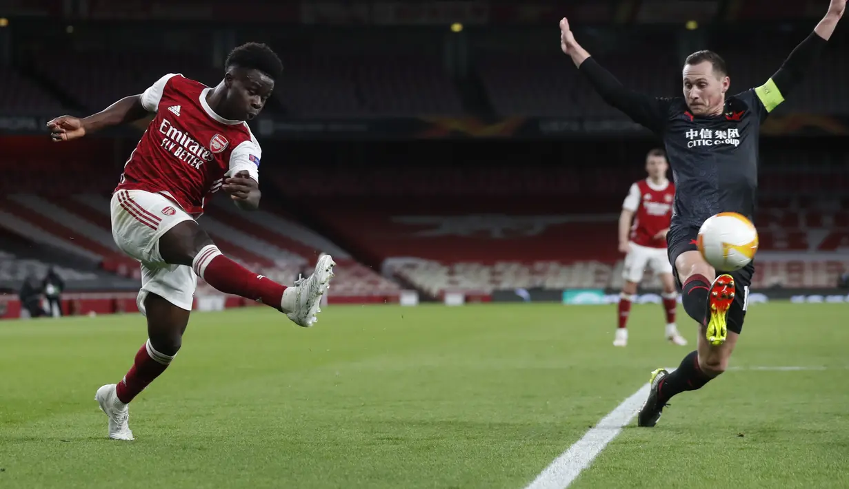 Bek Arsenal, Bukayo Saka mengumpan bola dari kawalan pemain Slavia Praha, Jan Boril pada pertandingan leg pertama perempat final Liga Europa di Stadion Emirates di London, Jumat (9/4/2021). Arsenal bermain imbang atas Slavia Praha 1-1.  (AP Photo/Alastair Grant)