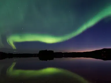 Cahaya aurora borealis menerangi langit malam Desa Erikslund di Vasternorrland County, Swedia (23/8). Fenomena alam yang indah ini terjadi pada bulan Maret-April dan September-Oktober. (AFP PHOTO/ JONATHAN NACKSTRAND)