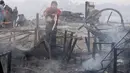 Seorang pria menyiram bara api yang masih tersisa akibat kebakaran yang melanda permukiman Cantagallo di Lima, Peru, Jumat (4/11). Petugas masih menyelidiki penyebab kebakaran di permukiman yang dihuni komunitas Suku Amazon itu. (REUTERS/Guadalupe Pardo)