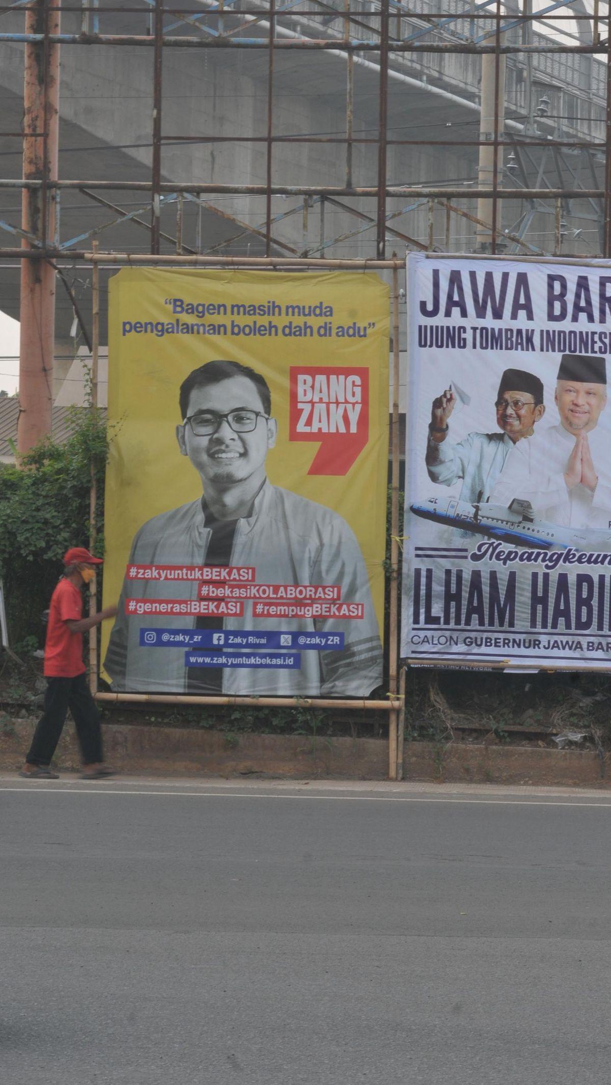 Seorang warga berjalan melewati alat peraga kampanye pilkada&nbsp;yang terpasang di Jalan Raya Bekasi, Bekasi, Jawa Barat, Kamis (11/7/2024).&nbsp;Merdeka.com/Imam Buhori