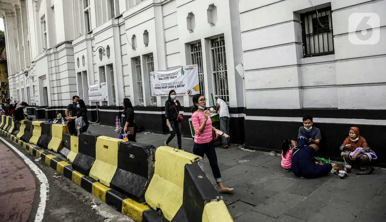 Pengunjung berjalan di depan kawasan wisata Kota Tua, Jakarta, Sabtu (15/5/2021). Pemerintah Provinsi DKI Jakarta menutup kawasan wisata Kota Tua untuk mengurangi kerumunan selama libur Lebaran 2021. (Liputan6.com/Faizal Fanani)