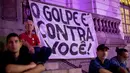 Para demonstran duduk mengelilingi spanduk dalam unjuk rasa di Sao Paulo, Brasil, Rabu (2/8). Diperlukan dua pertiga dari total suara atau 342 dari 513 suara untuk dapat melengserkan Michel Temer dari kursi kepresidenan. (AP/Silvia Izquierdo)