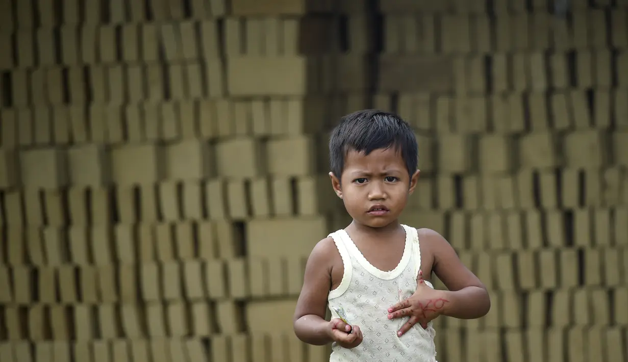 Seorang anak berdiri di depan tumpukan batu bata di sebuah pabrik batu bata di pinggiran Kajhu, Provinsi Aceh (18/11/2020). (AFP/Chaideer Mahyuddin)