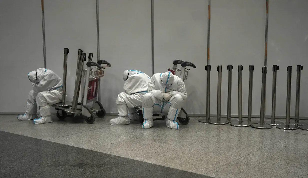 Pekerja Olimpiade dengan pakaian pelindung beristirahat setelah mereka membantu para pelancong di bandara Internasional Ibu Kota Beijing setelah Olimpiade Musim Dingin 2022, di Beijing, China, Senin (21/2/2022). (AP Photo/Alessandra Tarantino)