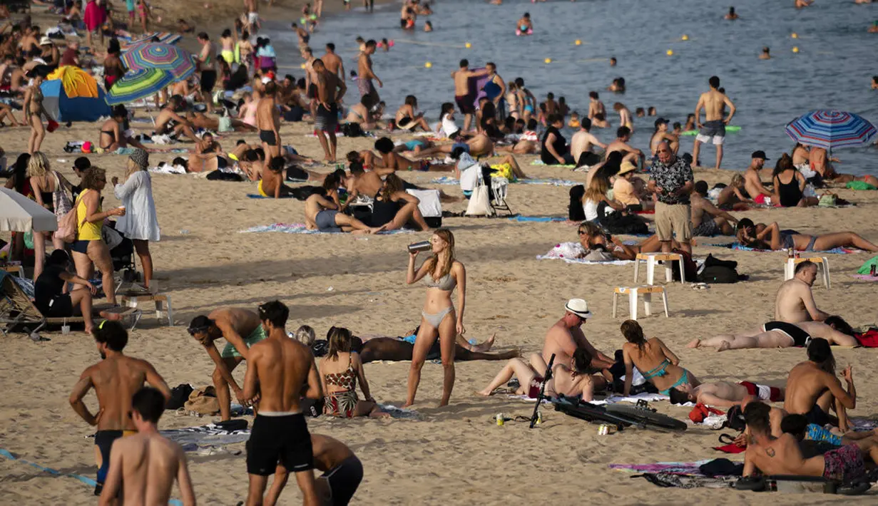 Seorang wanita minum sambil menikmati cuaca panas di pantai di Barcelona, Spanyol, Kamis (12/8/2021). Layanan cuaca nasional Spanyol memperingatkan suhu bisa mencapai 44 derajat Celcius (111 derajat Fahrenheit) di beberapa daerah dalam beberapa hari mendatang. (AP Photo/Joan Mateu Parra)